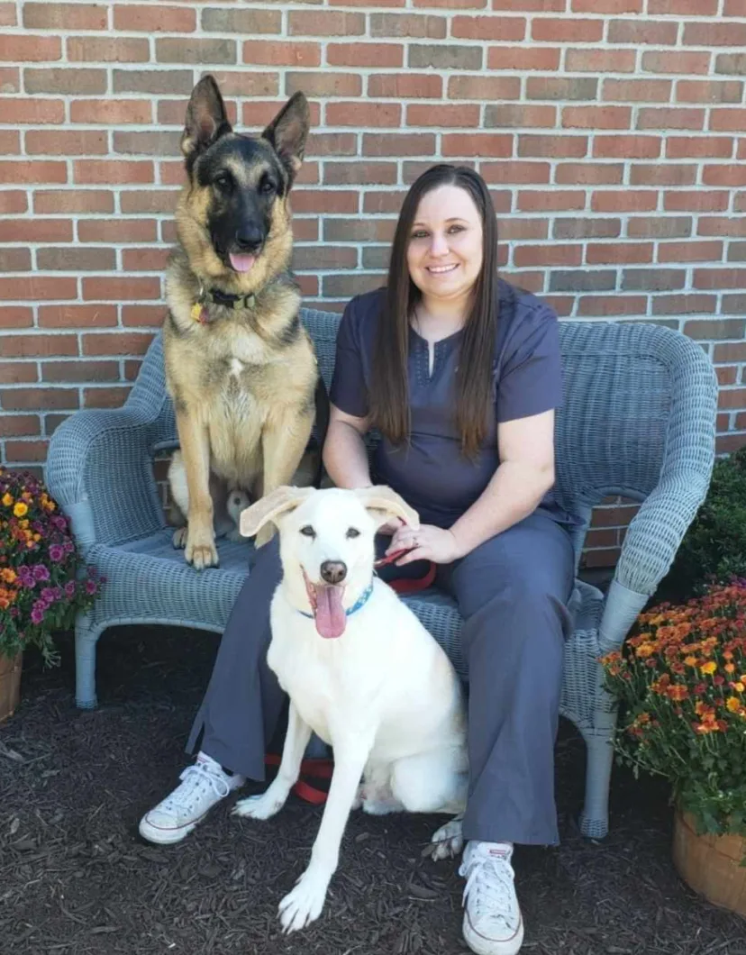 Assistant Manager Megan H posing with a German Shepherd and a white dog